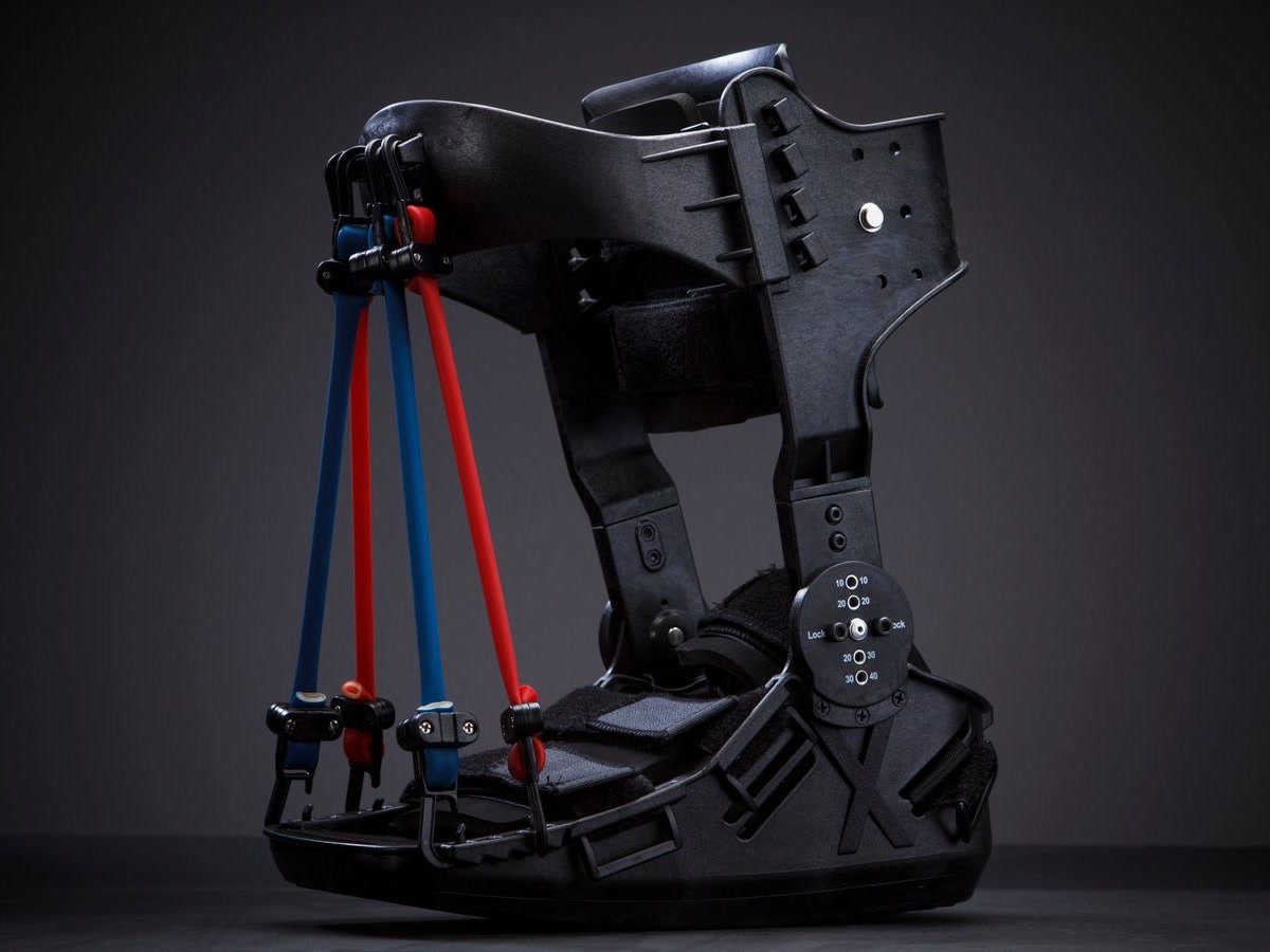 Rigid black ankle-foot brace with a range-of-motion dial and red and blue assist bands