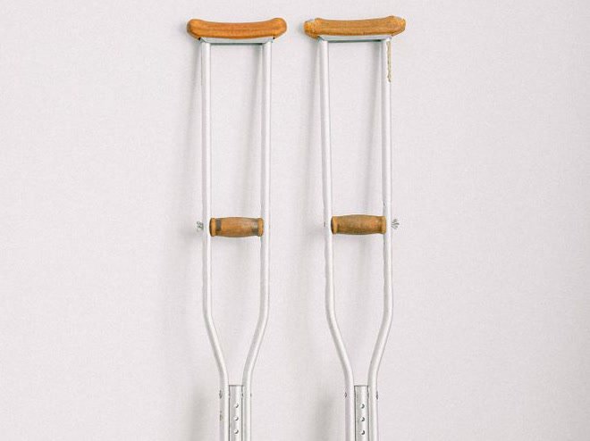 Pair of adjustable underarm crutches leaning against a wall